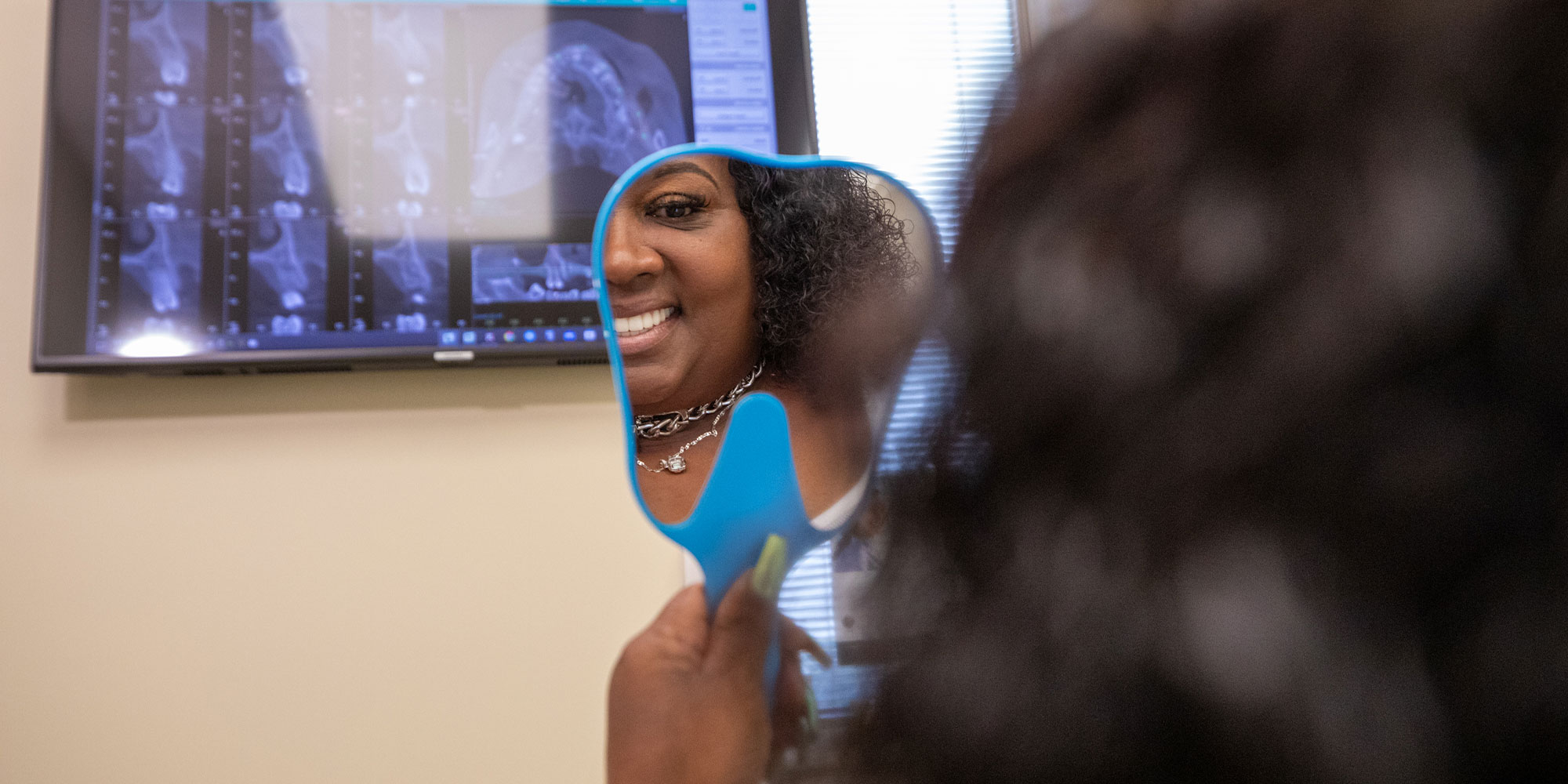 Patient holding up mirror smiling looking at them self after procedure